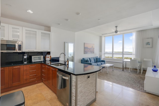 kitchen with light tile patterned floors, appliances with stainless steel finishes, a water view, a peninsula, and a sink