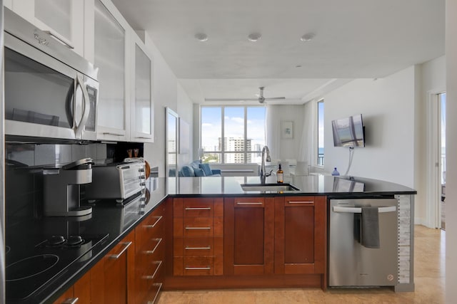 kitchen featuring stainless steel appliances, a peninsula, a sink, open floor plan, and modern cabinets