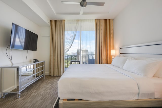 bedroom with access to exterior, a tray ceiling, ceiling fan, and a view of city