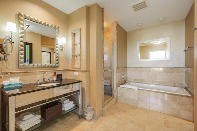 full bath featuring a stall shower, visible vents, a garden tub, vanity, and tile walls