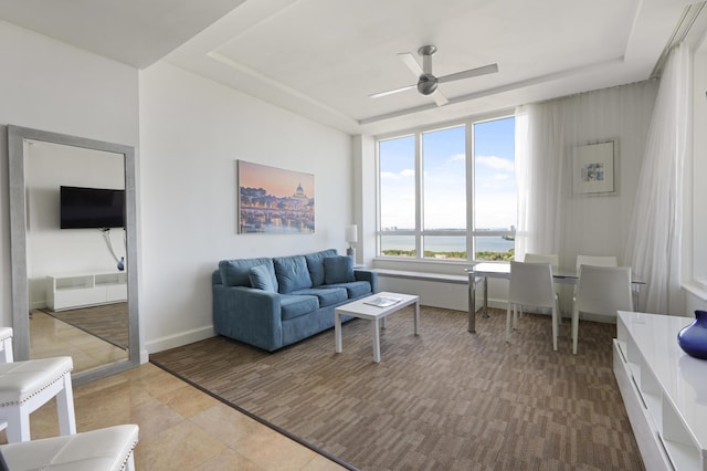 living room with ceiling fan, baseboards, a raised ceiling, and tile patterned flooring