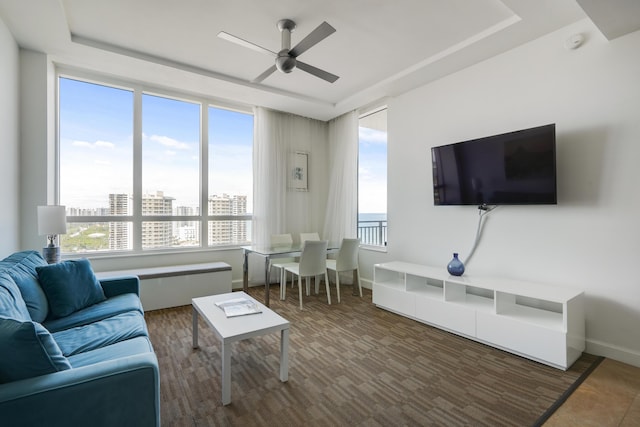 living area with wood finished floors, a ceiling fan, and baseboards