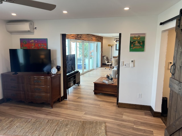 living area with a barn door, light wood-style flooring, recessed lighting, baseboards, and a wall mounted air conditioner