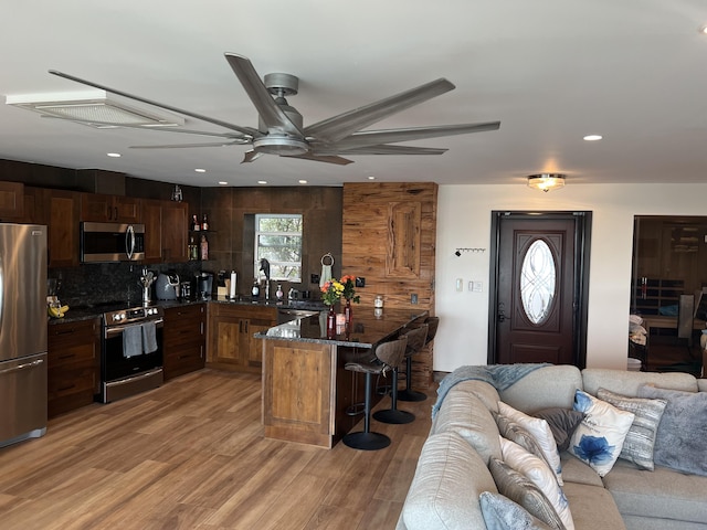 kitchen with a peninsula, appliances with stainless steel finishes, a breakfast bar, and open floor plan