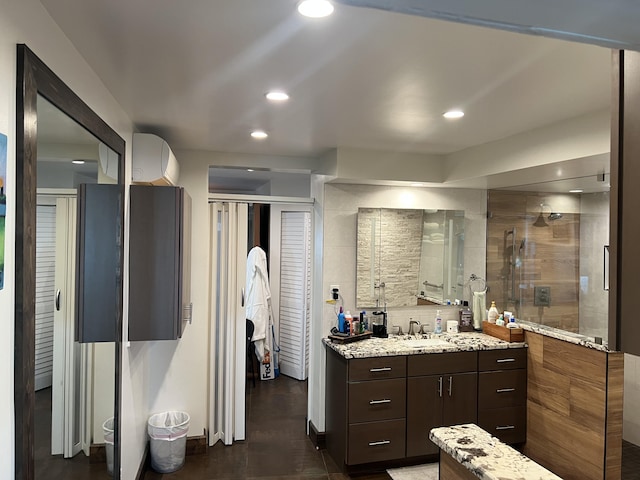 kitchen with recessed lighting, light stone countertops, a sink, and a wall mounted AC