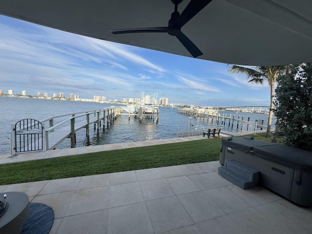 view of dock with a water view, a hot tub, a view of city, and boat lift