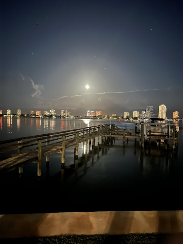 view of dock with a view of city lights and a water view