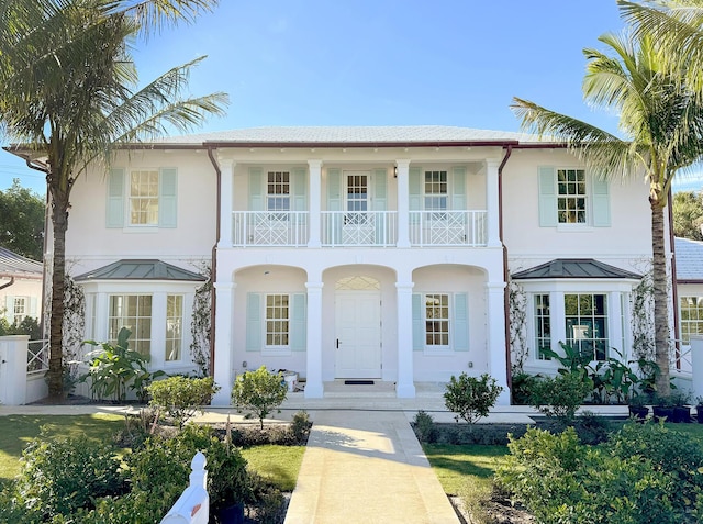 view of front of property featuring a porch, a standing seam roof, a balcony, and stucco siding