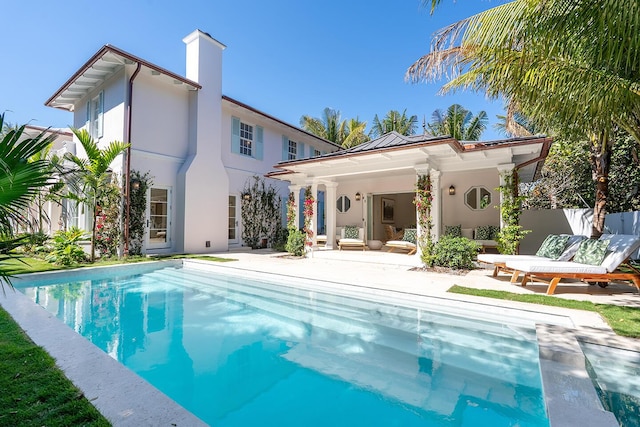 back of house with fence, a fenced in pool, stucco siding, a chimney, and a patio area