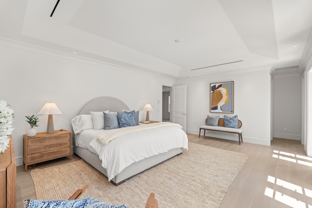 bedroom featuring light wood-style floors, a raised ceiling, ornamental molding, and baseboards