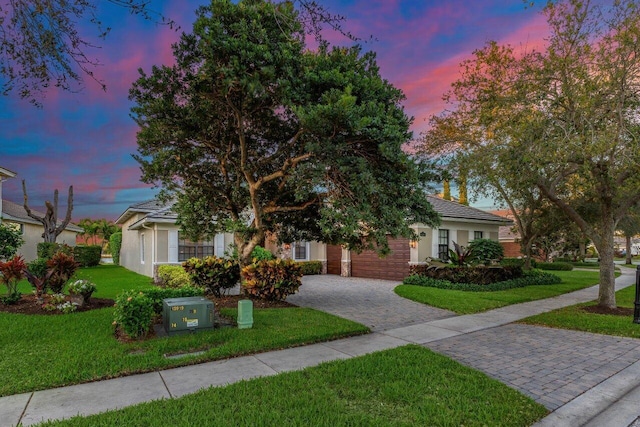 view of front of home featuring a front lawn, decorative driveway, a tile roof, and stucco siding