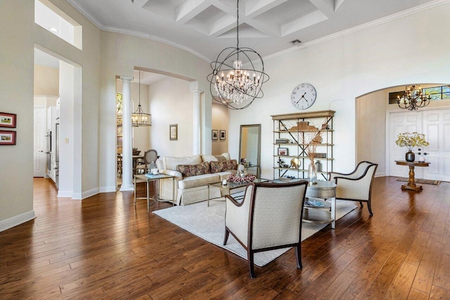 living room featuring decorative columns, a high ceiling, an inviting chandelier, coffered ceiling, and hardwood / wood-style floors