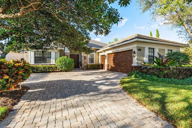 view of front facade with decorative driveway, an attached garage, and stucco siding