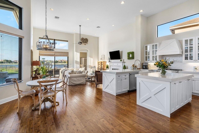 kitchen with dark wood finished floors, dishwasher, glass insert cabinets, open floor plan, and premium range hood