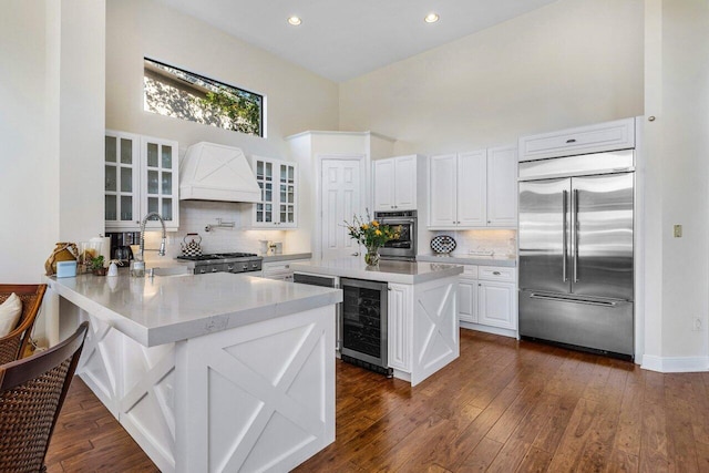 kitchen featuring wine cooler, stainless steel appliances, premium range hood, a peninsula, and white cabinets