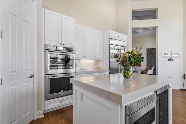 kitchen featuring dark wood-type flooring, beverage cooler, white cabinets, and built in appliances