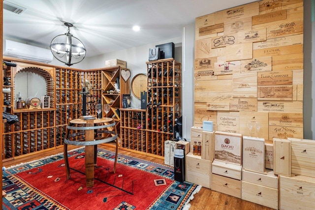 wine room featuring a wall unit AC, an inviting chandelier, visible vents, and wood finished floors