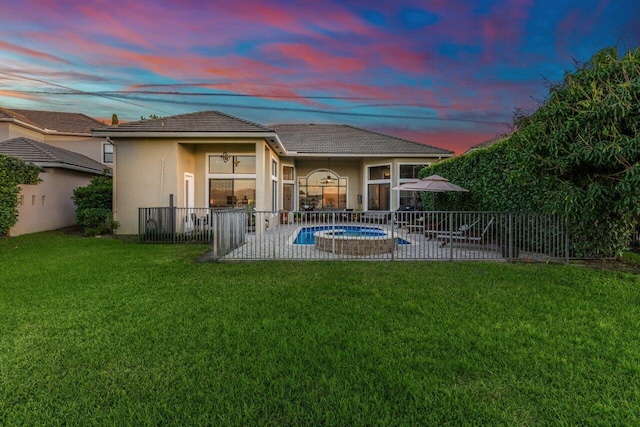 rear view of property with a patio, fence, a yard, a fenced in pool, and stucco siding