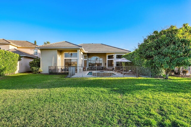 back of house featuring a lawn, a patio, a tile roof, fence, and stucco siding