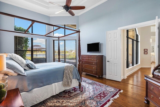 bedroom featuring crown molding, a high ceiling, baseboards, and wood finished floors