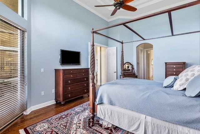 bedroom with baseboards, arched walkways, wood finished floors, a high ceiling, and crown molding