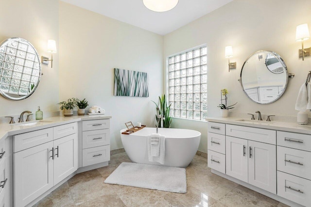 bathroom with a freestanding bath, two vanities, and a sink