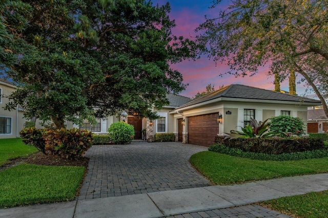 view of front facade with a garage, decorative driveway, a tile roof, and stucco siding