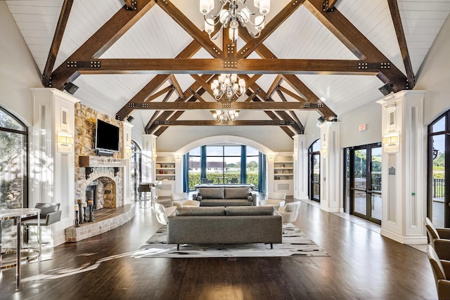 living area with a chandelier, a stone fireplace, wood finished floors, plenty of natural light, and decorative columns