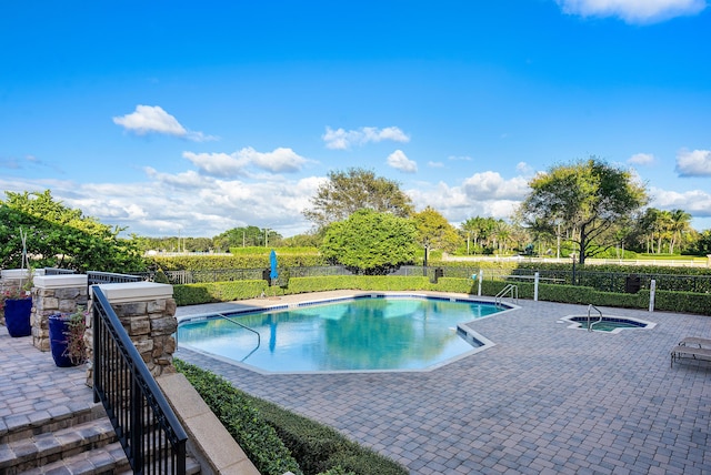 view of pool featuring a patio area, fence, a fenced in pool, and an in ground hot tub