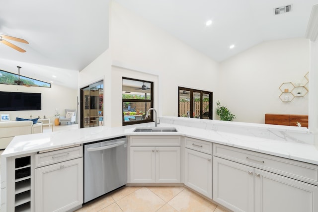 kitchen featuring visible vents, stainless steel dishwasher, vaulted ceiling, a sink, and light stone countertops