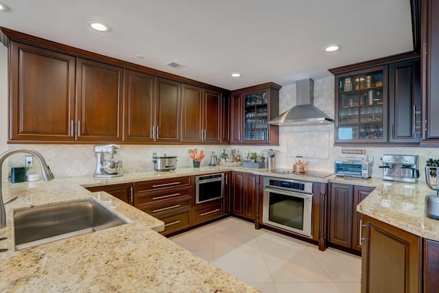 kitchen with light tile patterned floors, visible vents, a sink, stainless steel oven, and wall chimney exhaust hood