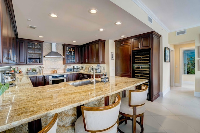 kitchen with visible vents, black appliances, and wall chimney exhaust hood