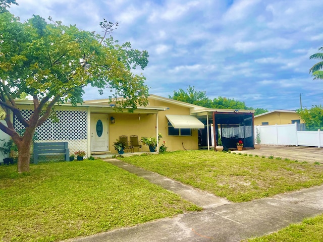 ranch-style home with a carport, fence, a front lawn, and stucco siding