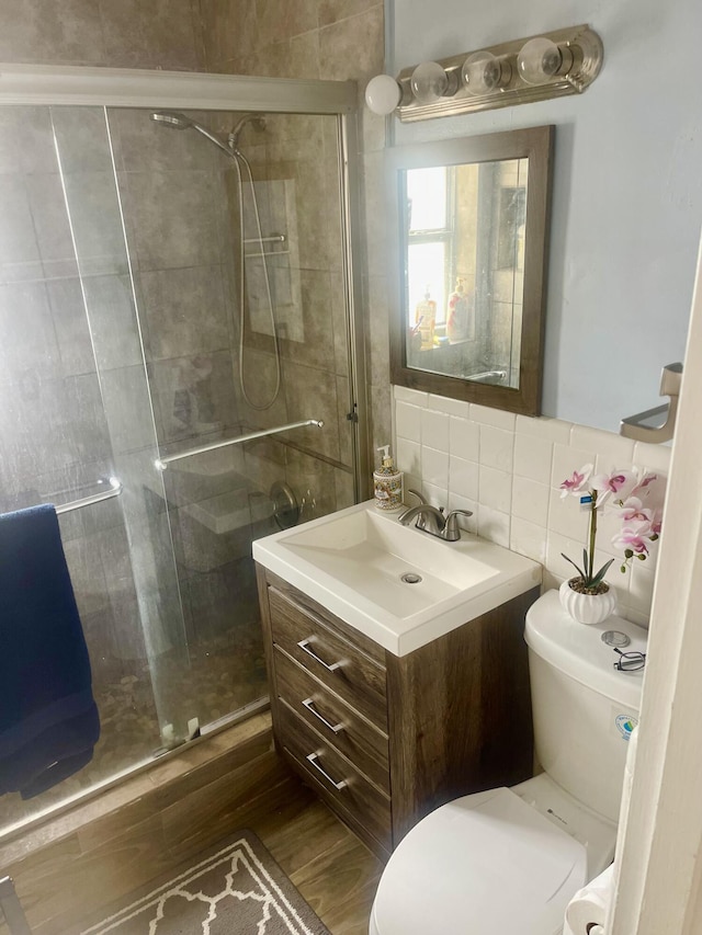 bathroom featuring decorative backsplash, toilet, vanity, a shower stall, and tile walls