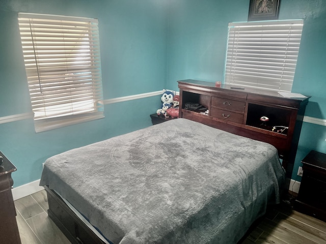 bedroom with multiple windows, light wood-style flooring, and baseboards