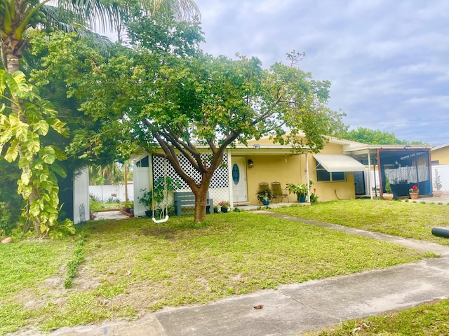 view of front facade with stucco siding, fence, and a front yard