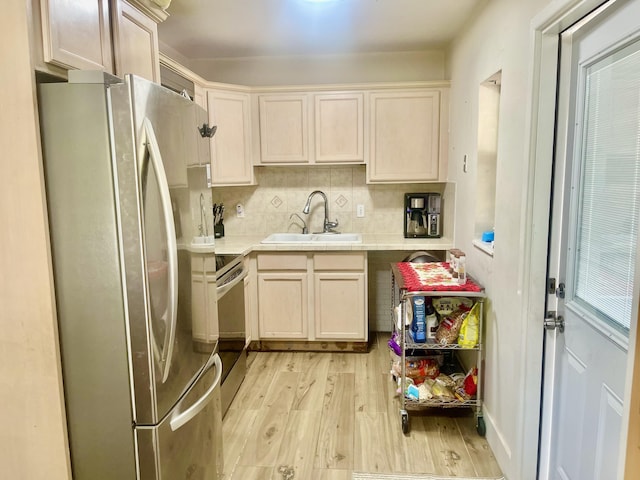 kitchen featuring tasteful backsplash, light countertops, appliances with stainless steel finishes, a sink, and light wood-type flooring