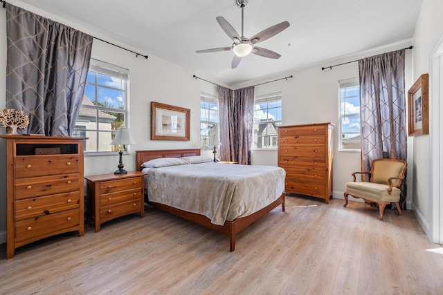 bedroom with ceiling fan, light wood finished floors, and baseboards