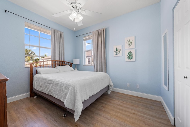 bedroom featuring light wood-type flooring, a ceiling fan, and baseboards