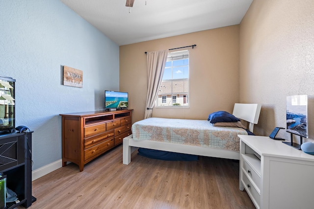 bedroom featuring light wood finished floors, a ceiling fan, and baseboards