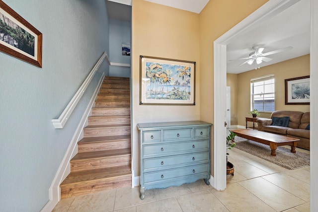 stairs featuring tile patterned flooring, a ceiling fan, and baseboards