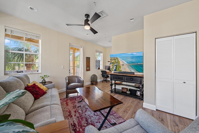 living room featuring ceiling fan, wood finished floors, visible vents, and baseboards