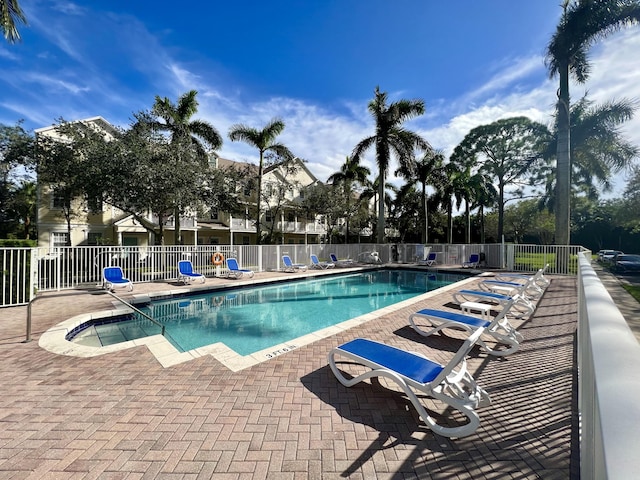 community pool with a patio area and fence