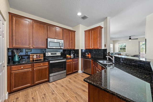 kitchen with light wood-style flooring, a sink, visible vents, appliances with stainless steel finishes, and tasteful backsplash