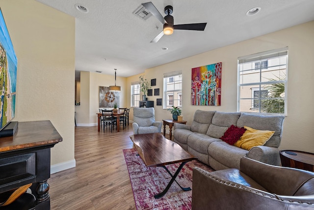 living area featuring a textured ceiling, a wealth of natural light, wood finished floors, and visible vents