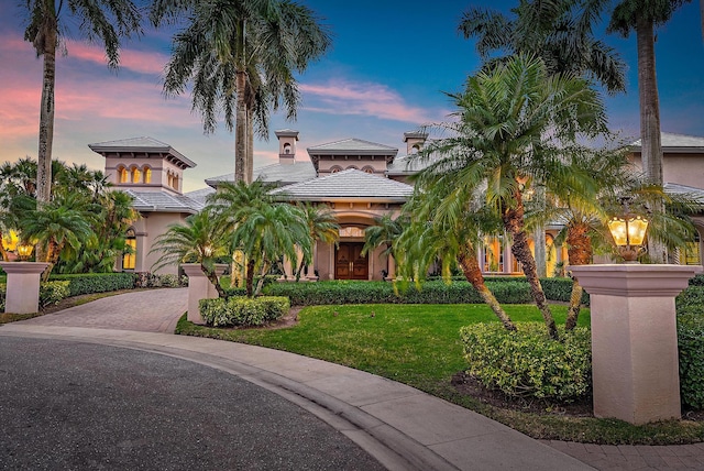 mediterranean / spanish-style home featuring stucco siding, decorative driveway, and a front yard