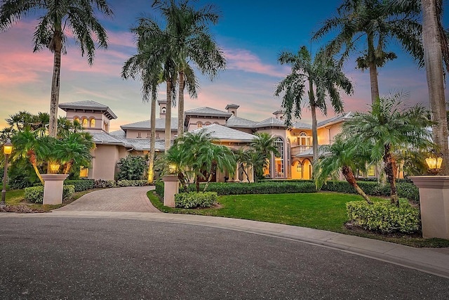 mediterranean / spanish house featuring decorative driveway, a yard, and stucco siding