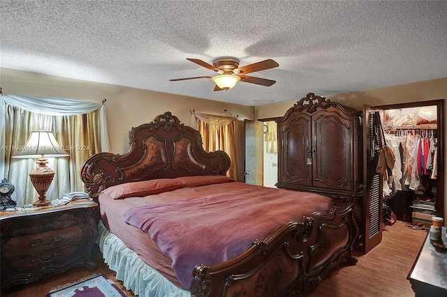 bedroom with a closet, a spacious closet, light wood-style floors, ceiling fan, and a textured ceiling