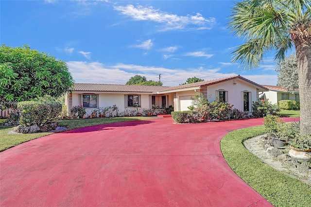 view of front of house with a garage, a tiled roof, concrete driveway, and stucco siding