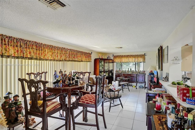 dining area featuring light tile patterned floors, visible vents, and a textured ceiling